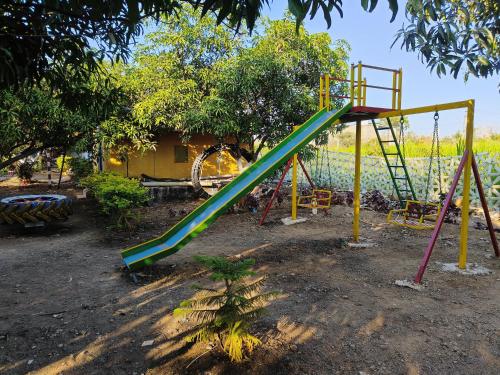 a playground with a green slide in a yard at Gokul farm house in Sasan Gir