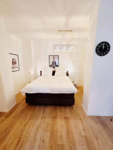1 dormitorio con 1 cama con sábanas blancas y suelo de madera en Wohngut-City Apt. 1 Zi. 1 DB + 1 EZ 34 qm mit Parkplatz en Hagen