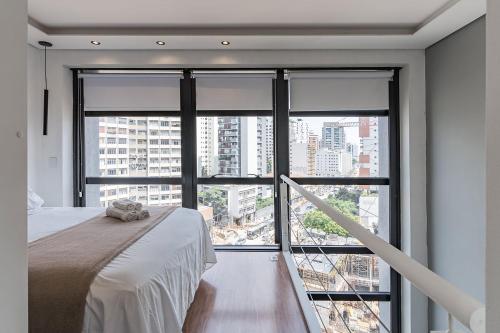 Un dormitorio con una cama y una ventana grande. en Flat duplex com serviço de camareira e enxoval completo - ao lado do parque Ibirapuera, en São Paulo
