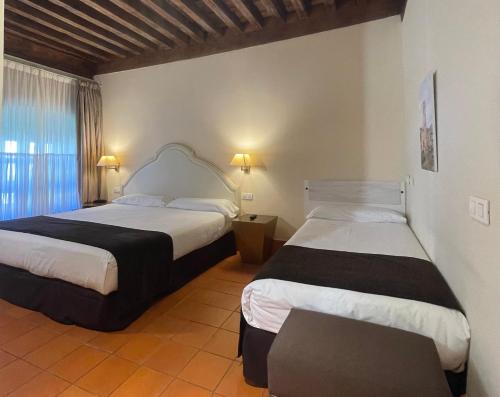 a bedroom with two beds and a window at Hotel San Antonio el Real in Segovia