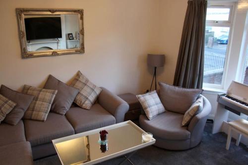 a living room with a couch and a mirror at Amazing 2-Bed Home w/ Private Garden Free Parking in Cardonald