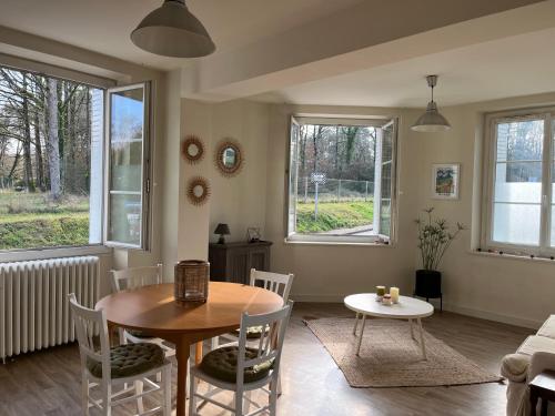 uma sala de estar com uma mesa, cadeiras e janelas em Maison au coeur des châteaux em Cour-Cheverny