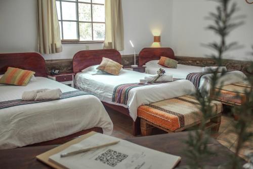 Cette chambre comprend 2 lits et une table. dans l'établissement Andean Wings Valley, à Urubamba