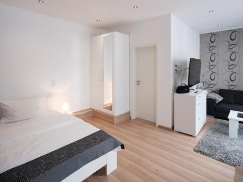 a white bedroom with a bed and a couch at city boarding lippstadt in Lippstadt