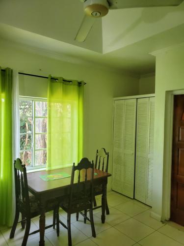 a dining room with a table and chairs and a window at Wizzy Apartment White River in Ocho Rios