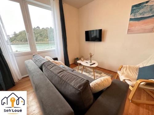 ein Wohnzimmer mit einem Sofa und einem TV in der Unterkunft Le batelier Seh’loué in Plérin