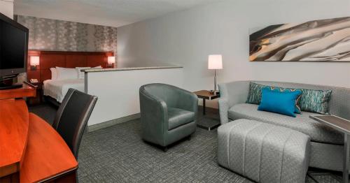 a hotel room with a bed and a couch and a tv at Courtyard by Marriott Orlando Lake Mary North in Lake Mary