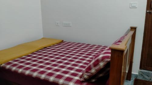 a bed with a red and white checkered blanket on it at Arasu Homestay in Antarasante