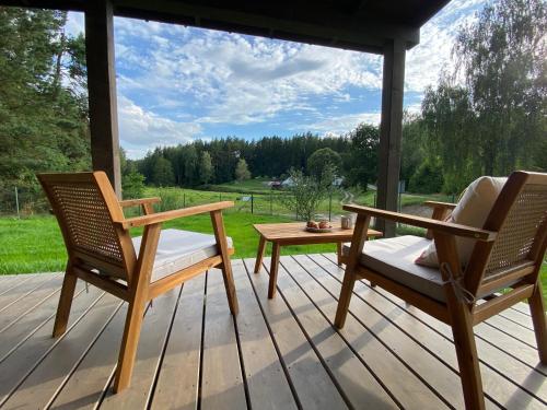 two chairs and a table on a porch with a view at Stodoła Drwęck in Drwęck