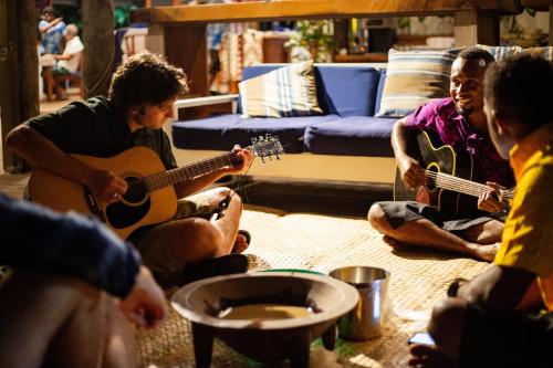 a group of people playing guitars in a living room at Blue Lagoon Beach Resort in Nacula Island