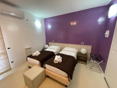 2 łóżka w pokoju z fioletowymi ścianami w obiekcie B&B Elia's w Cagliari