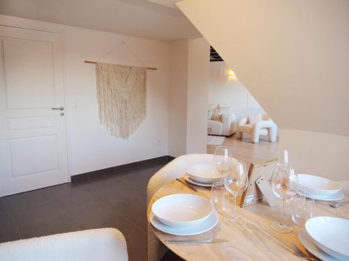 a dining room with a table with white plates and glasses at Magnifique cocon in Amiens