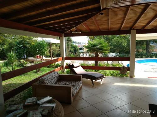 a patio with a couch and a chair and a pool at Suíte em Hotel Cotia in Vargem Grande Paulista