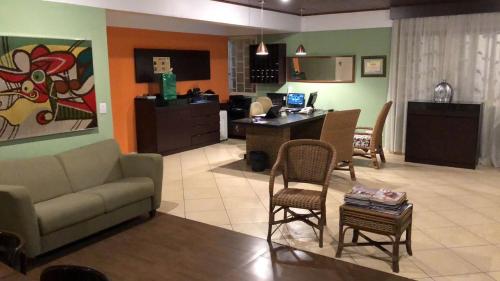 a living room with a couch and chairs and a desk at Suíte em Hotel Cotia in Vargem Grande Paulista