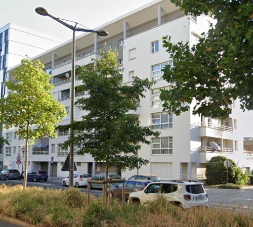 un bâtiment blanc avec des voitures garées devant lui dans l'établissement Pret à usage & Commodat Massy Grimaldi - 30 nuitées minimum - Salarié mobilité ou étudiant stagiaire, à Massy