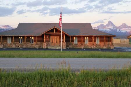 a log cabin with an american flag in front of it at Teton Crest Lodge Sleeps 24 Ideal Reunion Spot in Driggs