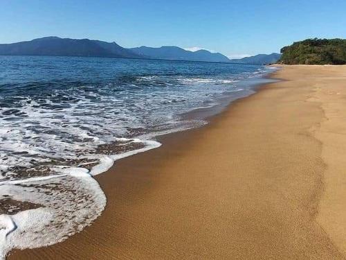 una spiaggia sabbiosa con onde che arrivano dall'oceano di Suítes Som do Mar a Caraguatatuba