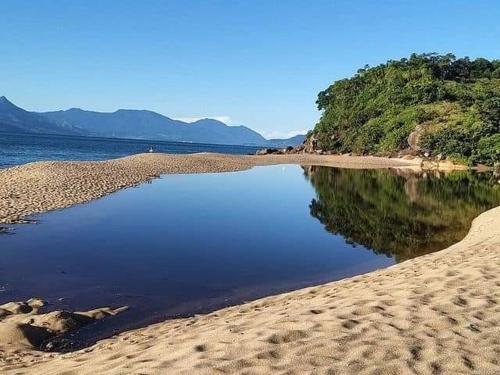 een strand met een zwembad aan de kust bij Suítes Som do Mar in Caraguatatuba