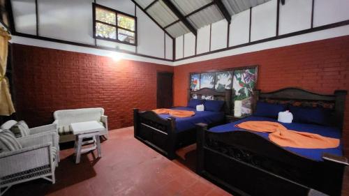 1 dormitorio con 2 camas, silla y ventana en Posada de Don Alonso, en Puerto Barrios