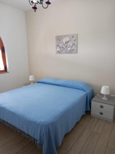 a bedroom with a bed with a blue bedspread at La Calla Bianca in Torre Dei Corsari