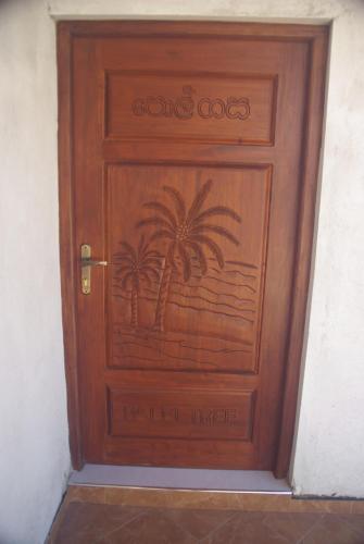 a wooden door with palm trees painted on it at King Coconut Lodge in Habaraduwa Central