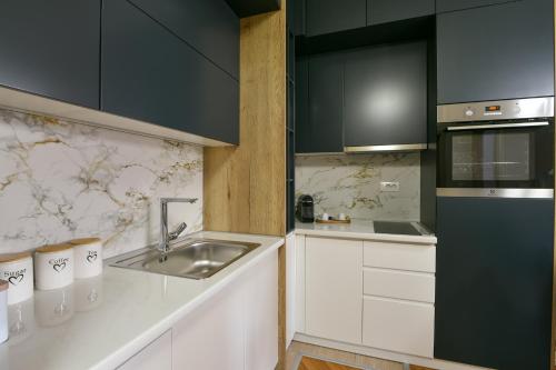 a kitchen with white cabinets and a sink at City Center Apartment Uzice in Užice