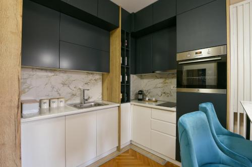 a kitchen with black cabinets and a blue chair at City Center Apartment Uzice in Užice