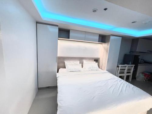 a bedroom with a white bed with a blue ceiling at Studio Anna in Cebu City