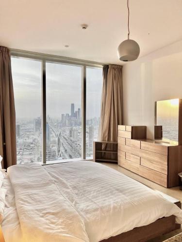 a bedroom with a large bed with a large window at Goatskynest Riyadh skyline view suites in Riyadh