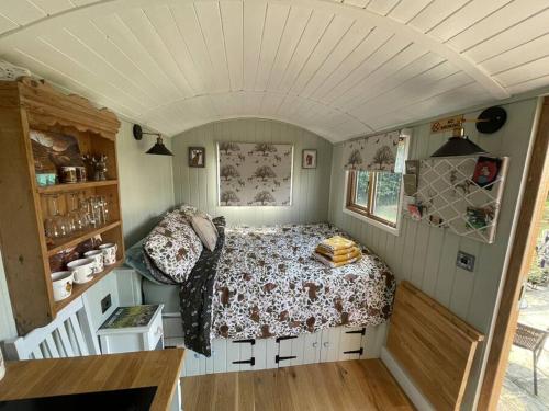 Forest View Shepherd Hut في Ewhurst: غرفة نوم بسرير في غرفة صغيرة