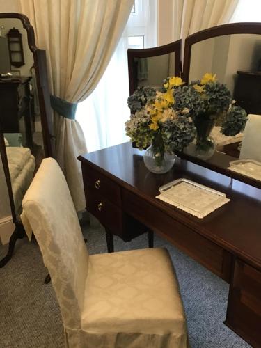 a desk with a vase of flowers and a chair at The Old Merchants House - The Vettriano Room in Southampton