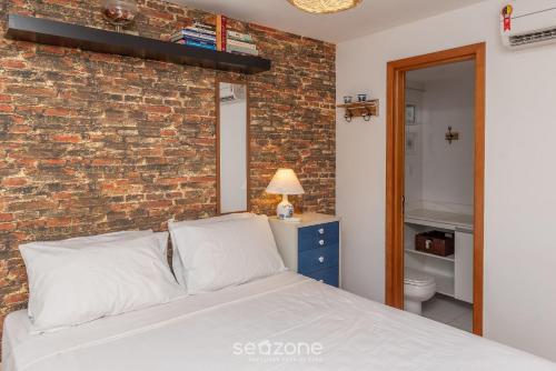 Un dormitorio con una pared de ladrillo y una cama en Apto luxuoso próximo ao mar OCH0511, en Salvador