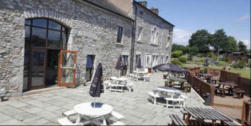 a patio with tables and umbrellas in front of a building at Yealands Delight in Warton