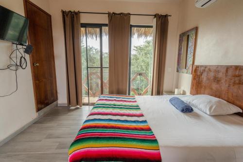 a bedroom with a bed with a colorful blanket on it at Casa Delfín Tulum in Macario Gomez