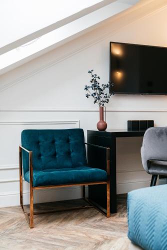 a blue chair sitting next to a desk with a tv at Central Palace - LoftAffair Collection in Kraków