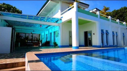 a house with a swimming pool in front of it at Couple room in Final Destination Resort in Bolinao