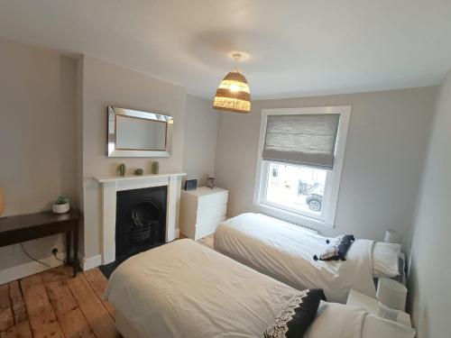 a bedroom with two beds and a fireplace at Welcoming 2 bed townhouse near town centre & beach in Kent