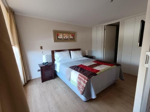 a bedroom with a bed and a table with a lamp at APART LOMAS DE SAN ANDRES concepción in Concepción