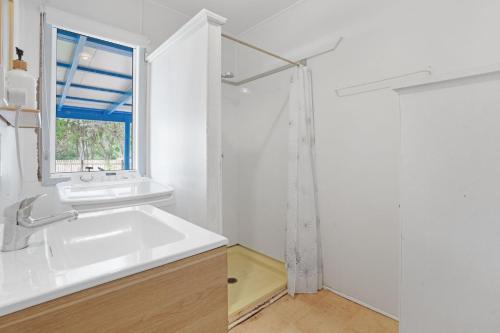 a white bathroom with a sink and a window at The Shack Rainbow Beach - Pets Welcome - Fully Fenced - Close to Beach in Rainbow Beach