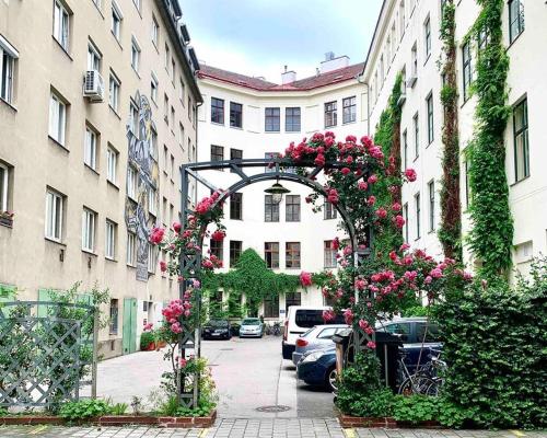 un arco con flores rosas en una calle de la ciudad en City Apartment Top Location, quiet and cozy Ideal to relax or work, en Viena
