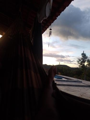 una persona sdraiata su un'amaca che guarda fuori da una finestra di Chácara Recanto das flôr a Pirenópolis