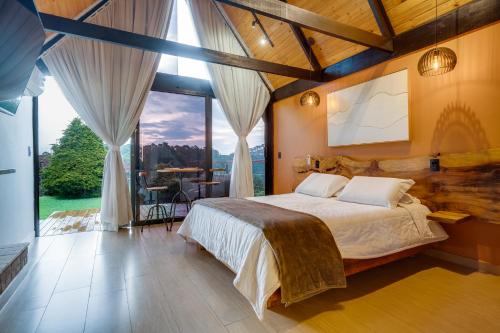 a bedroom with a large bed and a large window at Pousada das Pedras in Monte Verde