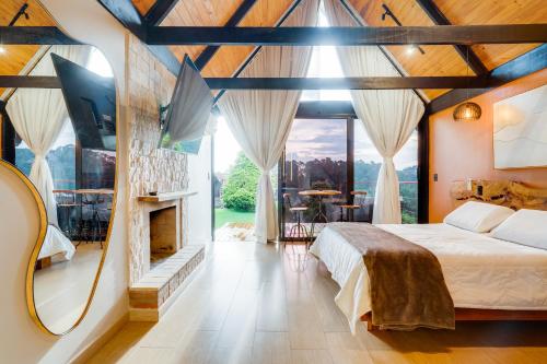 a bedroom with a large bed and a large window at Pousada das Pedras in Monte Verde