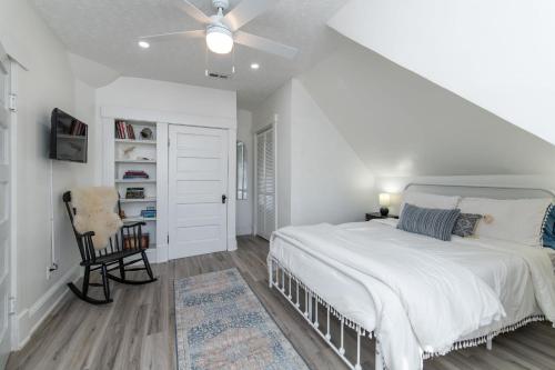a white bedroom with a bed and a chair at Loft on Capital - Ideally located to Distilleries in Frankfort