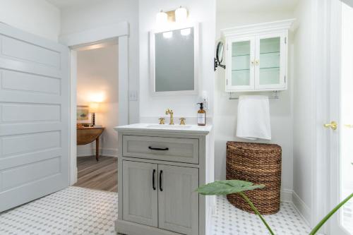 ein weißes Badezimmer mit einem Waschbecken und einem Spiegel in der Unterkunft Loft on Capital - Ideally located to Distilleries in Frankfort