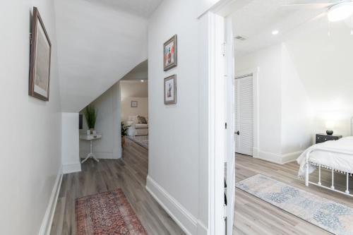a white bedroom with a bed and a hallway at Loft on Capital - Ideally located to Distilleries in Frankfort