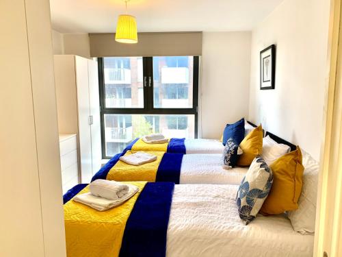 倫敦的住宿－Modern London Excel 2 Bedrooms 2 Bathrooms, Parking, Kitchen, Lounge, Balcony Apartment，一间卧室配有两张黄色和蓝色床单的床