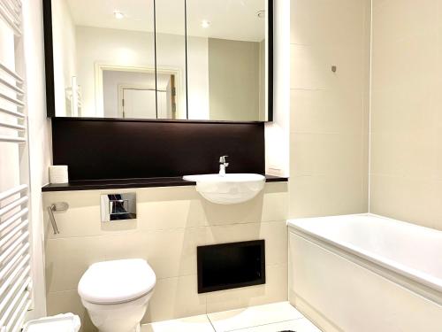 a bathroom with a toilet and a sink and a mirror at Modern London Excel 2 Bedrooms 2 Bathrooms, Parking, Kitchen, Lounge, Balcony Apartment in London