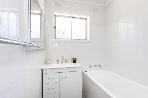 un bagno bianco con vasca e lavandino di The Nest Lavington ad Albury