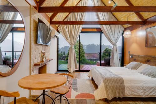 a bedroom with a bed and a table at Pousada das Pedras in Monte Verde